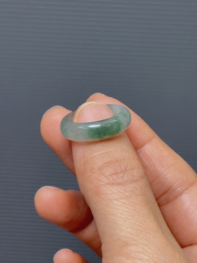 May include: A jade green ring with a smooth, polished finish. The ring is a simple band with a slightly rounded shape.
