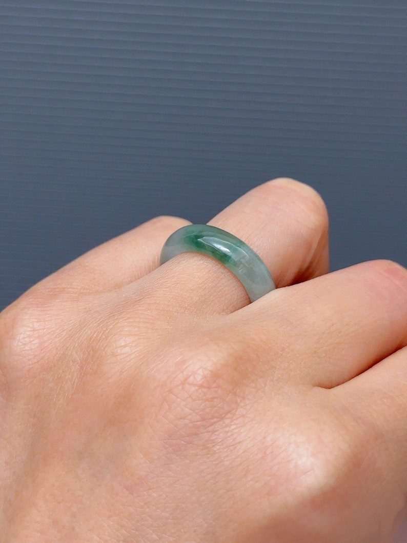 May include: A jade green ring with a smooth, polished finish. The ring is worn on a finger.