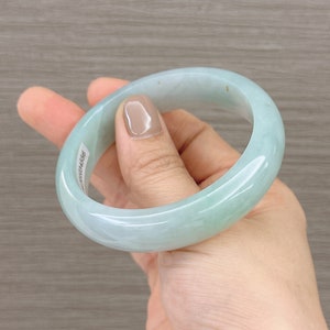 May include: A light green jade bangle bracelet. The bracelet is smooth and polished.