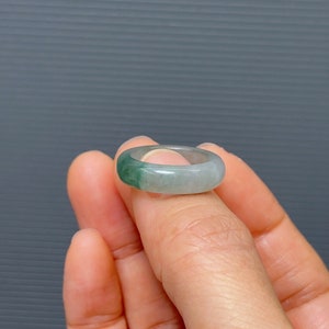 May include: A jade ring with a light green and white color gradient. The ring is made of natural jade and has a smooth, polished finish.