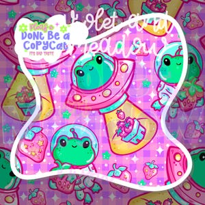 Può includere: Un motivo stravagante con rane dei cartoni animati con caschi e tute spaziali, con fragole e UFO. Lo sfondo è un motivo a quadri rosa e viola. Il testo include "Please Don't Be a CopyCat" e "Violet and Meadow".
