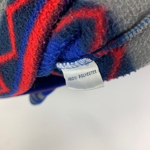 Puede incluir: Una etiqueta de tela blanca con el texto "100% POLYESTER" impreso en negro.