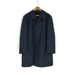 May include: A dark blue wool coat with a button closure and two pockets. The coat is hanging on a wooden hanger.