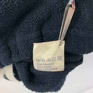May include: A beige care label with black washing instructions and text that reads "Wash Separately/ Iron on reverse Made in Bangladesh".