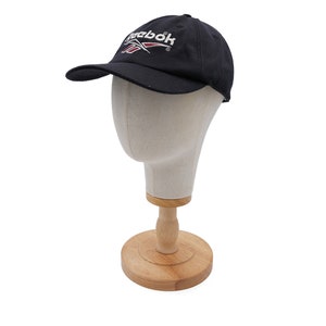 May include: A black baseball cap with a white Reebok logo and a red accent. The cap is on a mannequin head.