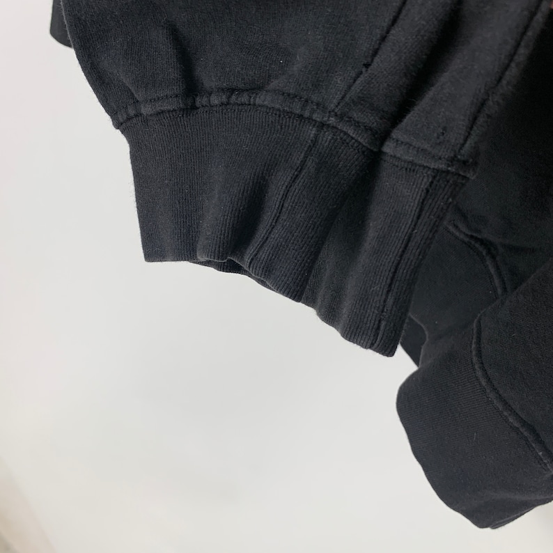 May include: Close-up of the black ribbed cuff of a black sweatshirt.