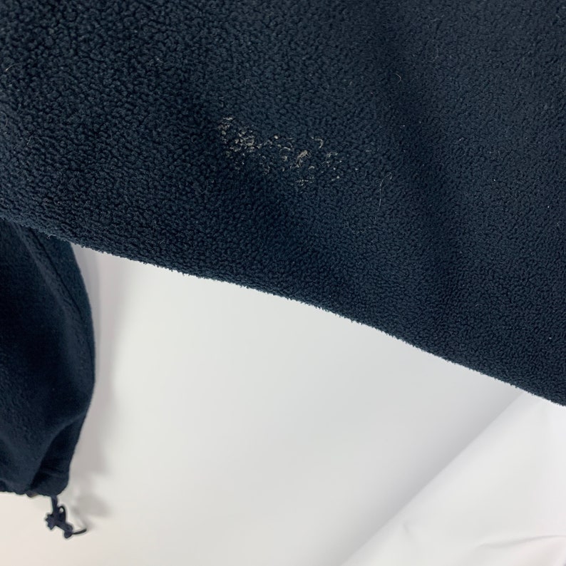May include: A black fleece jacket with a drawstring at the bottom.