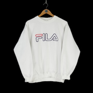 Pode incluir: Camisola branca com um logotipo FILA azul e vermelho.