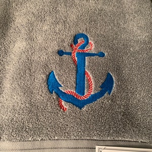 May include: Gray bath towel with an embroidered blue anchor and red rope. The towel has the text "THREADHOUSE BATH" on a white tag.