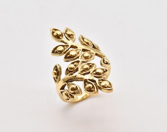 Puede incluir: Un anillo de color dorado con un diseño de hoja. El anillo está hecho de metal y tiene un diseño delicado e intrincado.