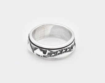 May include: A silver spinning ring with a design of a camel and other desert animals. The ring is made of metal and has a smooth, polished finish.