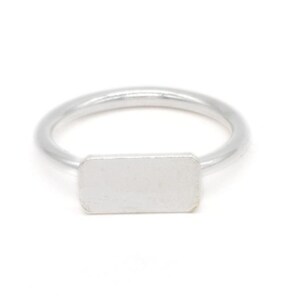 Puede incluir: Un anillo de plata con una banda de forma rectangular.