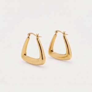 May include: A pair of gold-toned hoop earrings featuring a distinct triangular shape with rounded corners. The earrings have a smooth, polished metallic finish and include a hinged post mechanism at the top for secure closure and comfortable wear.