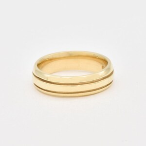 May include: A gold wedding band with two grooves around the center.