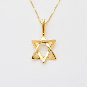 May include: A gold-colored Star of David pendant necklace. The pendant is a six-pointed star with a hollow center. The necklace chain is a delicate gold color and is attached to the pendant with a small loop.
