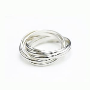 May include: A silver ring featuring five intertwined bands. The bands have a smooth, polished finish, forming a woven pattern. The ring is displayed on a white backdrop, accentuating its metallic lustre.