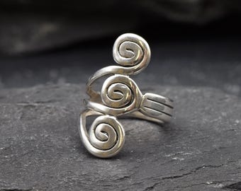 Könnte beinhalten: Ein silberner Ring mit drei Spiralmotiven. Der Ring ist offen und verstellbar.