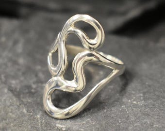 May include: A silver ring with a unique, abstract design. The ring is made of smooth, polished metal and features a series of interconnected loops and curves.