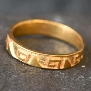 Op de afbeelding: Een gouden ring met een decoratief patroon rond de hele band.