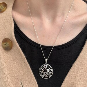 May include: A silver necklace with a round pendant featuring Hebrew lettering. The pendant is a circle with a detailed design of Hebrew letters.