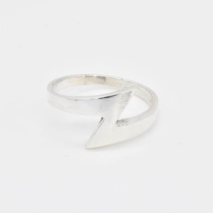May include: Silver ring with a lightning bolt design. The ring is open and adjustable.