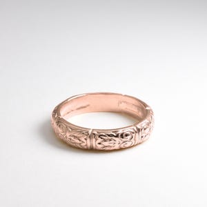 Könnte beinhalten: Ein Roségold-Ehering mit einem komplizierten, gravierten Blumenmuster.