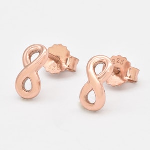 May include: A pair of rose gold infinity symbol earrings. The earrings are made of sterling silver and have a 925 stamp on the back.