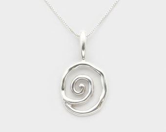 May include: A silver pendant necklace featuring a spiral design within an oval frame. The pendant hangs from a delicate silver chain. The necklace is displayed against a plain white background, highlighting the jewelry's minimalist style.