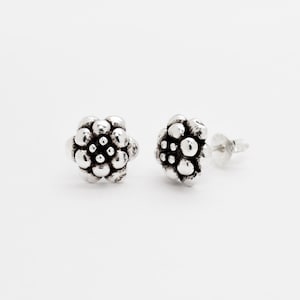 Peut inclure: Une paire de boucles d'oreilles en argent avec un motif floral texturé.