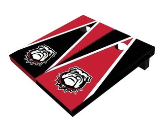 May include: A red and black regulation size cornhole set with a University of Georgia Bulldogs logo. The set includes two boards with a black background and a red triangle with a white border. The Bulldogs logo is in the center of the triangle.