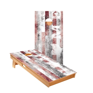 May include: A wooden cornhole game with a red, white, and gray distressed wood grain design. The boards have the word "Game On" written on them in white paint.