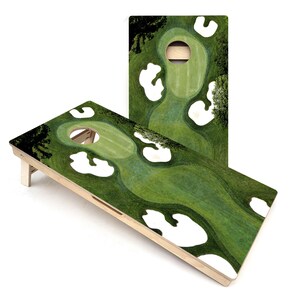 May include: A wooden cornhole game with a green and white golf course design. The game is set up on a white surface.