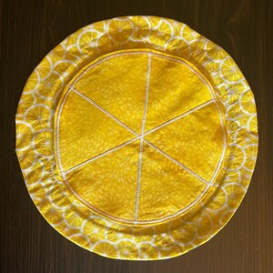 inside of the bag, layed flat. the backing is a fabric patterned with lemon wedges, the pockets are stitched to look like a big slice of lemon