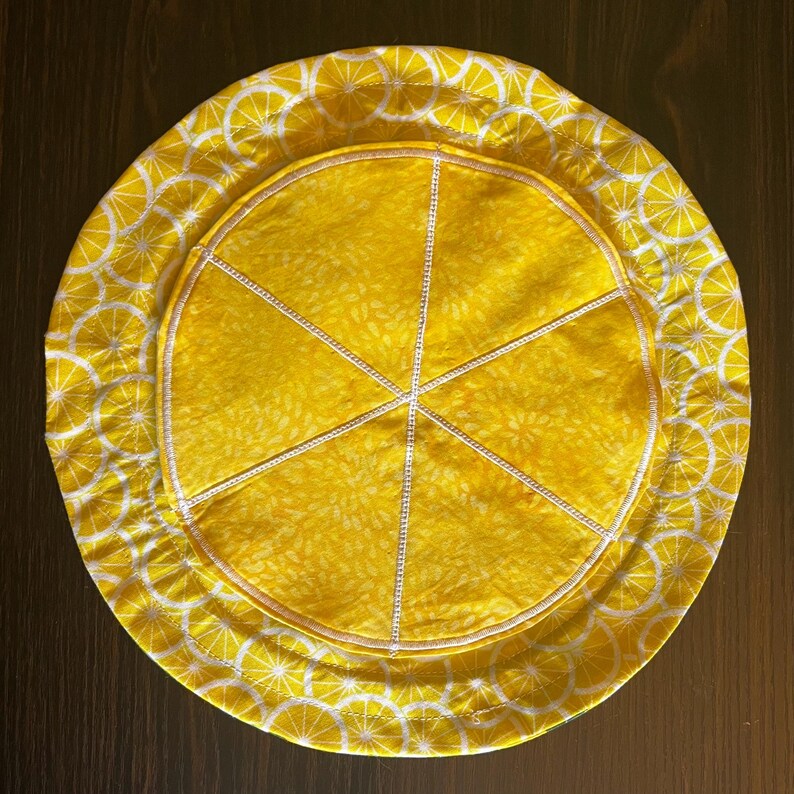 inside of the bag, layed flat. the backing is a fabric patterned with lemon wedges, the pockets are stitched to look like a big slice of lemon