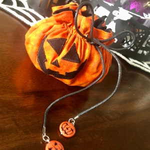 the bag closed in front of a decorative haloween background. the face of the jack-o-lantern is clearly visible
