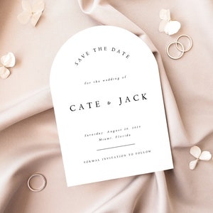 May include: A white save the date card with an arch shape at the top. The text reads "Save the Date" for the wedding of "Cate & Jack" on Saturday, August 20, 2024 in Miami, Florida. The card also says "Formal Invitation to Follow".