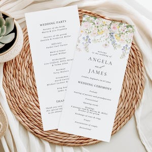 May include: Two wedding ceremony programs with floral accents, on a woven placemat. The programs feature the names "ANGELA and JAMES" and "WEDDING PARTY". The programs are white with black text, and a succulent plant is visible.