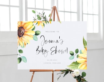 May include: Welcome to Joanna's Baby Shower sign with a watercolor sunflower design. The sign is white with black text and the date 24.08.2021 and location London, England.