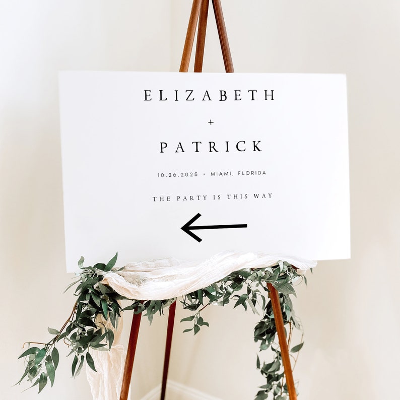 May include: White wedding sign with black text that reads "Elizabeth + Patrick 10.26.2026 - Miami, Florida The Party is This Way" with a black arrow pointing left.