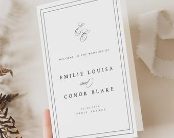 May include: A white wedding invitation with a black border and text. The invitation reads "Welcome to the Wedding of Emilie Louisa and Conor Blake" with the date and location, Paris, France.