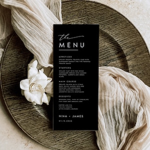 May include: Black and white wedding menu card with the text "the MENU" at the top. The menu lists appetizers, starters, main course, desserts, coffee and tea, and after-dinner liqueurs. The bottom of the card reads "NINA + JAMES 07.12.2022".