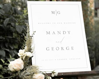 May include: White wedding welcome sign with black text. The sign reads "M/G Welcome to our wedding Mandy and George 28.08.2021 London England".