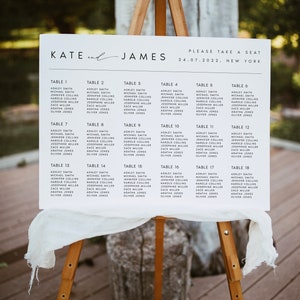 May include: A wooden easel displays a white sign with the names "Kate and James" and a seating chart for a wedding. The chart lists names under table numbers, with the date and location at the top.