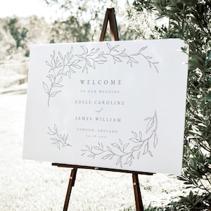 Puede incluir: Señal de bienvenida de boda blanca con un diseño floral y el texto "Bienvenido a nuestra boda Adele Caroline y James William Londres, Inglaterra 24.08.2023"