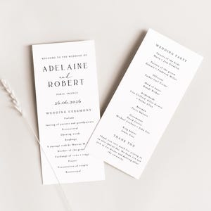 May include: Two white wedding ceremony programs with black text. The left program reads "Welcome to the Wedding of Adeline et Robert" and includes the date "26.06.2016". The right program lists the wedding party and a thank you message.