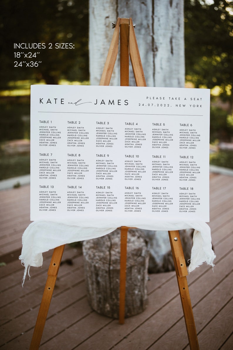 May include: A white wedding seating chart on a wooden easel, listing names under table numbers. The sign includes the names "Kate" and "James" and the date 24.07.2022, with the location "New York". The sign is 18"x24" or 24"x36".
