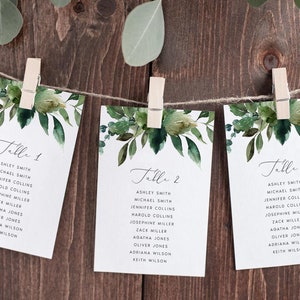 Puede incluir: Tres tarjetas blancas con diseños florales de acuarela verde y texto negro. Las tarjetas están etiquetadas como "Mesa 1", "Mesa 2" y "Mesa 3" y enumeran los nombres para cada mesa.