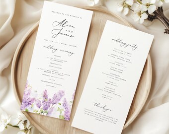May include: Two wedding ceremony programs on a wooden tray. The programs are white with black text and a watercolor floral design in shades of purple. The programs include the names "Alice and Jane" and the date "July 4th, 2024".