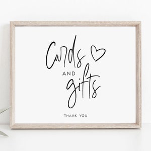 Könnte beinhalten: Ein weißes Schild mit schwarzem Rahmen und dem Text "Cards and gifts" mit einem Herzsymbol. Der Text "Thank you" befindet sich am unteren Rand des Schildes.