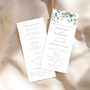 Peut inclure: Deux programmes de cérémonie de mariage blancs avec du texte noir. Un programme répertorie le cortège nuptial, y compris l'officiant, les demoiselles d'honneur et les garçons d'honneur. L'autre programme souhaite la bienvenue au mariage d'Abigail et Robert à Paris, France, le 26 juin 2026.